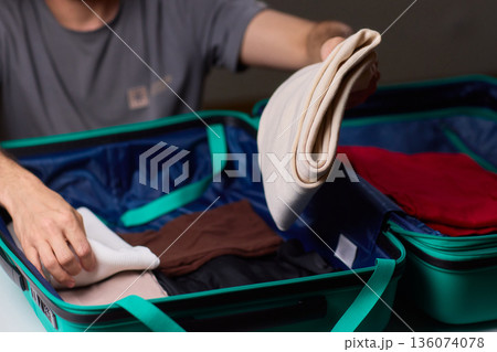 Organizing clothes before travel, Traveler arranges garments meticulously in their suitcase, An individual smoothly folds clothing and organizes suitcase for upcoming departure 136074078