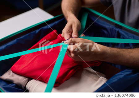 Hands tightening teal travel luggage strap, Closeup of hands attaching teal strap to luggage, Detailed shot of hands securing bright teal bag strap during travel preparation 136074080