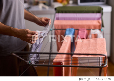 Home interior scene with clothing being gently organized and dried, Domestic chore involving male hands carefully placing cotton underwear on mesh sorter in apartment 136074270