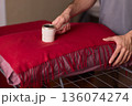 Hands cleaning red wool scarf with lint roller across fringed fabric, closeup texture, warm bedroom lighting, careful motion, pet hair removal, garment ready for outing 136074274