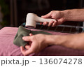 Close view of lint tool on wool, Man using lint roller to clean wool hat texture, Detailed scene of hand grooming fuzz from soft knitted wool hat with lint roller 136074278