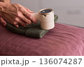 Close view of lint tool on wool, Man using lint roller to clean wool hat texture, Detailed scene of hand grooming fuzz from soft knitted wool hat with lint roller 136074287