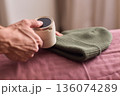 Close view of lint tool on wool, Man using lint roller to clean wool hat texture, Detailed scene of hand grooming fuzz from soft knitted wool hat with lint roller 136074289