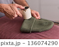 Close view of lint tool on wool, Man using lint roller to clean wool hat texture, Detailed scene of hand grooming fuzz from soft knitted wool hat with lint roller 136074290