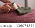 Close view of lint tool on wool, Man using lint roller to clean wool hat texture, Detailed scene of hand grooming fuzz from soft knitted wool hat with lint roller 136074859
