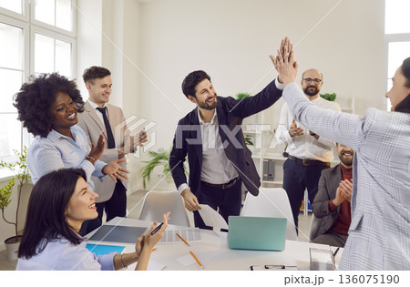Two men giving high five celebrating business achievement on workplace in office. Two men giving high five celebrating business achievement on workplace in office. 136075190