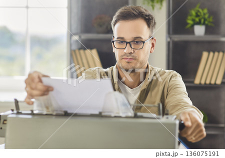 Focused writer editing page on vintage typewriter at modern home office workspace 136075191