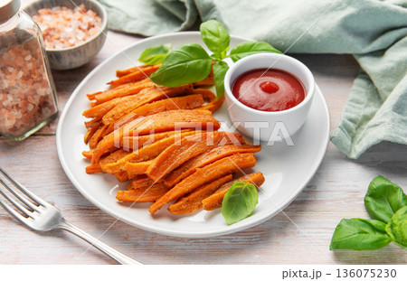 Sweet potato fries with ketchup and fresh basil leaves 136075230