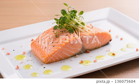 Fresh salmon fillet with microgreens, pink salt and olive oil drops served on white plate, gourmet seafood dish presentation 136075684