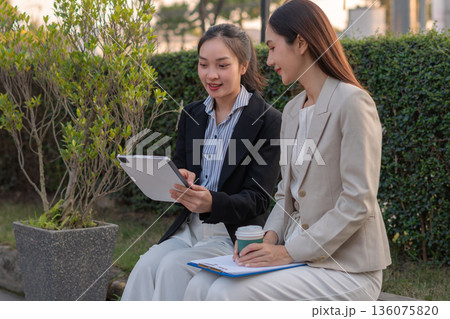 businesswomen team reviewing and discussing a business project outside office building. 136075820