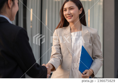 Business women shake hands after agreeing to start a new project successfully. 136075829