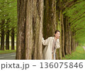 新緑のメタセコイヤ並木道を笑顔で散歩する女性 136075846