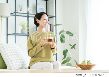 リビングで紅茶を飲むミドルの女性 136076142