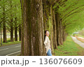 新緑のメタセコイヤ並木道を笑顔で散歩する女性 136076609