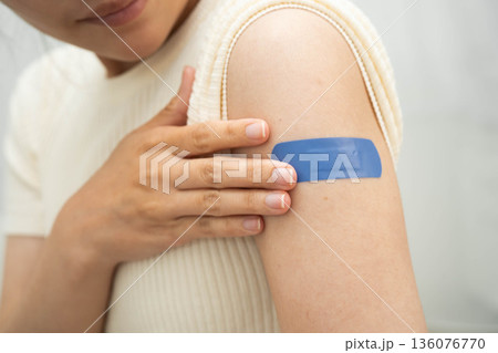HPV, Human papillomavirus, Asian young woman receiving vaccine with blue bandage. 136076770