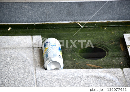 側溝の水に浮くポイ捨てされたアルミ缶 136077421
