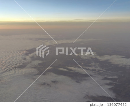 Aerial view of swirling cloud system above rough terrain highlighting atmospheric activity and contrast Aerial view of swirling cloud system above rough terrain highlighting atmospheric activity and contrast 136077452