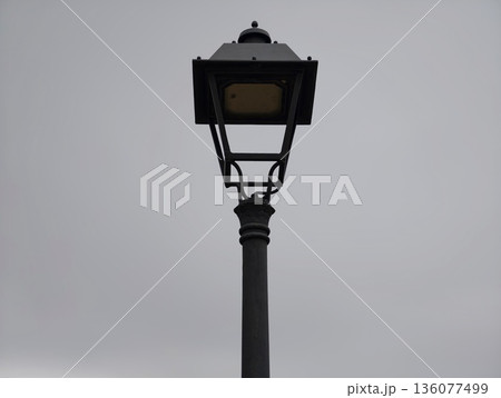 Desolate lamp silhouette, Lone street lamp stands against heavy overcast sky in tranquil cityscape 136077499