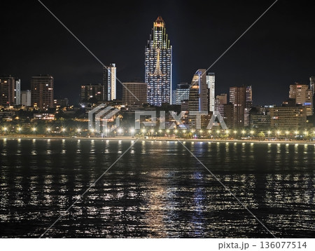Nighttime city lights along river, Calm waterfront illuminated by shimmering lamps and reflections Nighttime city lights along river, Calm waterfront illuminated by shimmering lamps and reflections 136077514