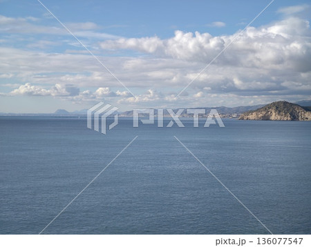Calm sea with cloudy backdrop, Vast peaceful waters meeting far shoreline under cloudy layered sky Calm sea with cloudy backdrop, Vast peaceful waters meeting far shoreline under cloudy layered sky 136077547