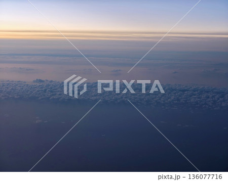 Dawn illuminates distant sky, Bright morning glow spreads over horizon with extended cloud shapes Dawn illuminates distant sky, Bright morning glow spreads over horizon with extended cloud shapes 136077716