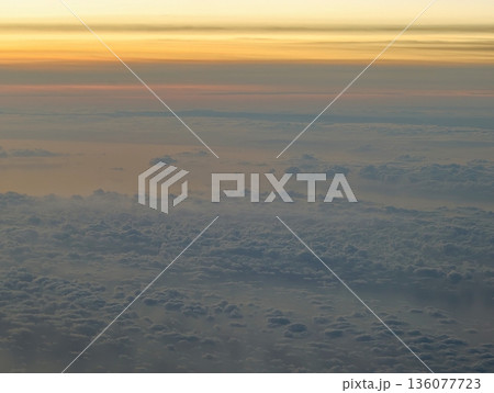 Sunset sky vista, Birds eye view revealing warm sunset glow over mountain range and drifting clouds 136077723