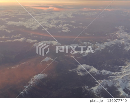 Vivid sunrise over mountain peaks, Aerial view showcasing colorful daylight and snowy terrain Vivid sunrise over mountain peaks, Aerial view showcasing colorful daylight and snowy terrain 136077740