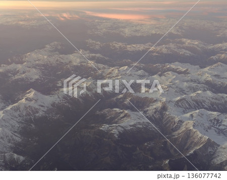 Shadowed peaks meet warm horizon, Jagged mountain ridges at twilight reveal striking geological features Shadowed peaks meet warm horizon, Jagged mountain ridges at twilight reveal striking geological features 136077742
