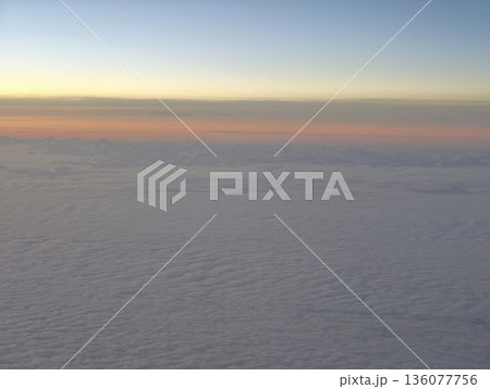 Serene dawn with soft cloudy horizon, Tranquil sunrise casting warm tones over expansive clouds Serene dawn with soft cloudy horizon, Tranquil sunrise casting warm tones over expansive clouds 136077756