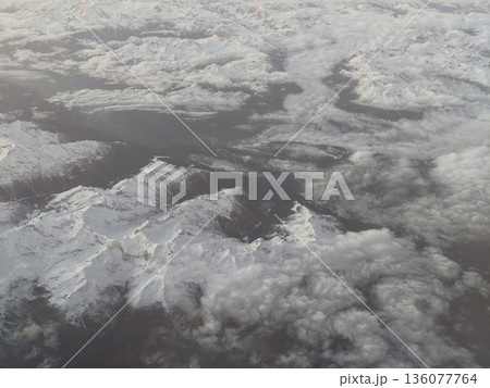 Cloudcovered mountain peaks in silence, Serene scene of snowy mountains veiled by clouds and mist Cloudcovered mountain peaks in silence, Serene scene of snowy mountains veiled by clouds and mist 136077764