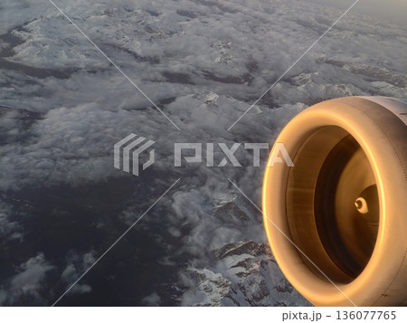 Highaltitude view of jet with illuminated turbine face above snowy terrain and distant horizon 136077765