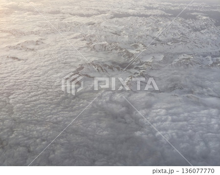 Visual depiction of textured cloud layers across icy mountain landscapes with warm horizon lighting Visual depiction of textured cloud layers across icy mountain landscapes with warm horizon lighting 136077770