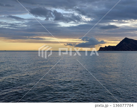 Serene sunset over water, Peaceful ocean scene illuminated by golden sunset and gentle clouds 136077784