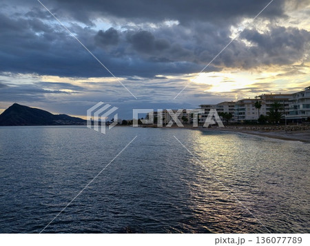 Serene evening seaside landscape, Calm sunset beside island silhouette reflecting in gentle water 136077789