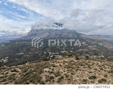 Rugged valley and cloudy peak, Dramatic scene of distant village beneath cloudy mountain top Rugged valley and cloudy peak, Dramatic scene of distant village beneath cloudy mountain top 136077852