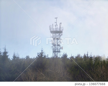 Secluded natural landscape featuring communication mast with various transmitting units amidst misty clouds Secluded natural landscape featuring communication mast with various transmitting units amidst misty clouds 136077888