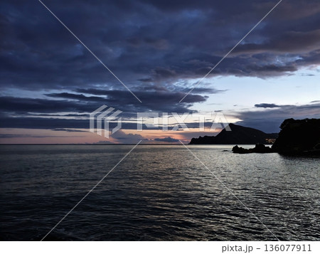 Serene twilight bathes peaceful harbor village with reflected lights and soft cloud layers Serene twilight bathes peaceful harbor village with reflected lights and soft cloud layers 136077911