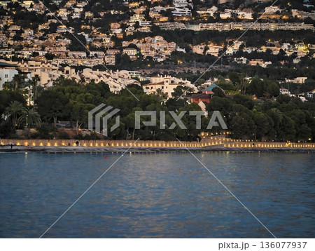 Peaceful waters with glowing homes, Gentle ripples dance across tranquil water under starry sky 136077937