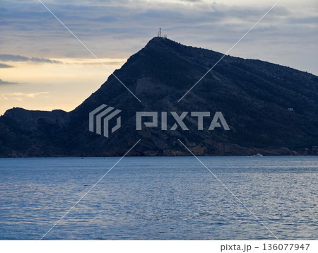 Tranquil sea with mountain peak, Calm ocean scene with ridge and sunset lighting for explorers Tranquil sea with mountain peak, Calm ocean scene with ridge and sunset lighting for explorers 136077947