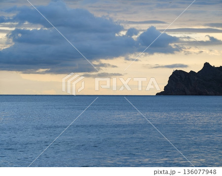 Gentle dawn over calm waters, Serene morning view featuring tranquil water and distant landforms 136077948