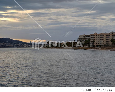 Tranquil dusk waterfront scenery, Quiet harbor scene with gentle waves and distant cityscape Tranquil dusk waterfront scenery, Quiet harbor scene with gentle waves and distant cityscape 136077953