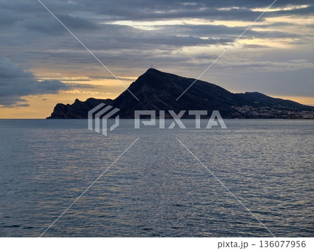 Dark island with stormy waters, Atmospheric seascape with storm clouds and mountain silhouette 136077956