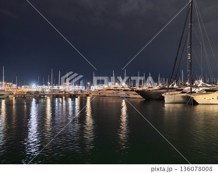 Serene waterfront view, Tranquil marina illuminated by lights reflecting softly on water surface Serene waterfront view, Tranquil marina illuminated by lights reflecting softly on water surface 136078008
