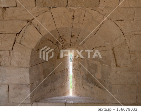 Historic tunnel features radiant light pathway, Ancient stone corridor with luminous slit and shadow play 136078032