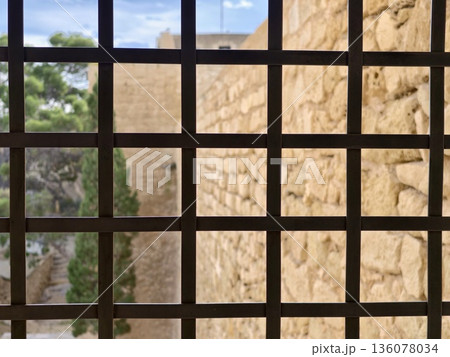 Foreground iron grid with distant scenery, Closeup of iron mesh against blurred rocky background Foreground iron grid with distant scenery, Closeup of iron mesh against blurred rocky background 136078034