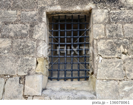 Weathered stone with iron bars, Scene depicting aged stone wall with fortified iron barred window 136078061