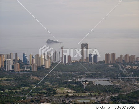 Serene waterfront with distant islet, Urban seafront featuring clustered towers and calm waters Serene waterfront with distant islet, Urban seafront featuring clustered towers and calm waters 136078080