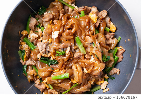 Thai food (Pad See Ew), Stir-fried rice noodles with soy sauce, pork, egg, and kale in cooking pan Thai food (Pad See Ew), Stir-fried rice noodles with soy sauce, pork, egg, and kale in cooking pan 136079167