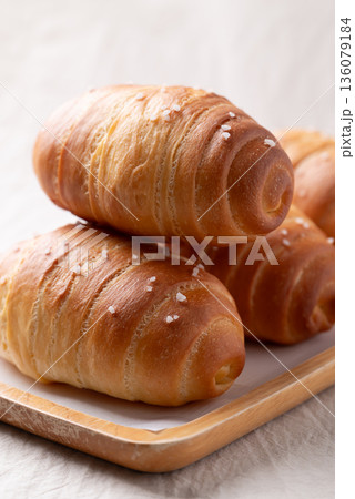Salt bread (Shio pan) with sea salt flakes on a wooden plate, Japanese bakery style Salt bread (Shio pan) with sea salt flakes on a wooden plate, Japanese bakery style 136079184