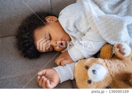 Baby sleeping peacefully with teddy bear on couch Baby sleeping peacefully with teddy bear on couch 136080189